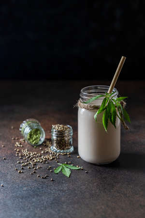Homemade vegan milk from hemp seeds in a glass jar on a dark concrete background. Non-dairy milk. Selective focus, copy space.の写真素材
