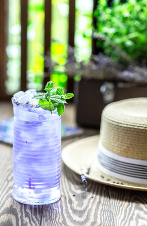 Lavender lemonade and ice cubes on a wooden table. Summer drink, iced tea. Selective focus