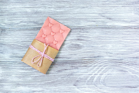 Pink chocolate whole bar decorated with slices of fruit nuts and slices against gray background....