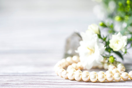 Beautiful white pearl necklace with white flowers. Close up, selective focus