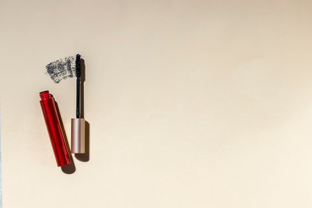 Black mascara and brush on beige background. Hard light. Cosmetics and fashion concept.