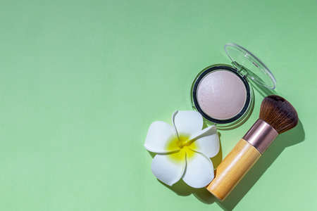 Makeup brush and powder on a green background. Cosmetics and fashion concept. Hard light.の写真素材