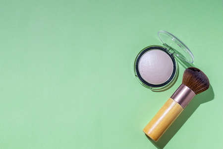 Makeup brush and powder on a green background. Cosmetics and fashion concept. Hard light.の写真素材