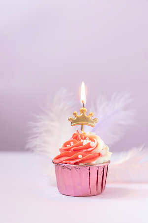 Composition with festive cupcakes with pink cream and a candle on a pink background.の写真素材