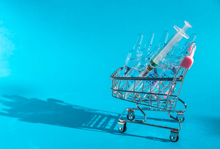 A lot of ampoules for injection in a basket on a blue background. Selling medicines. Online Drug store. Direct hard light with shadows.の写真素材