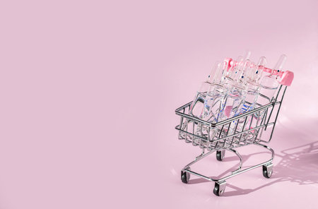 A lot of ampoules for injection in a basket on a pink background. Selling medicines. Online Drug...