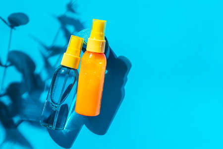 Cosmetic spray bottle blue and yellow with transparent liquid on a blue background. Spa cosmetics. Natural skincare. Copy space, top view.の写真素材