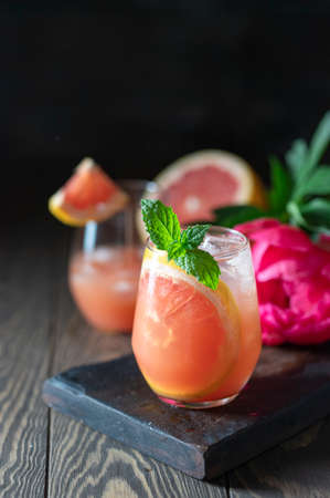 A glass of freshly squeezed grapefruit juice and mint on a dark wooden table. Refreshing summer cocktail. Selective focus, copy space.の写真素材