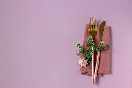 Knife and fork and linen napkin on pink background. Holiday celebration. Copy spaceの写真素材