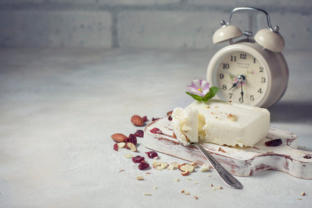 Breakfast of cottage cheese with nuts on a white wooden board. Selective focus