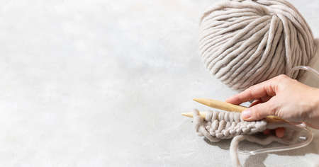Female hands knitting with gray wool. Close up of knitting wooden knitting needles. Zero waste concept. Hand knitting. Copy spaceの写真素材