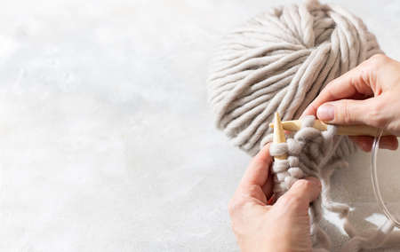 Female hands knitting with gray wool. Close up of knitting wooden knitting needles. Zero waste concept. Hand knitting. Copy spaceの写真素材