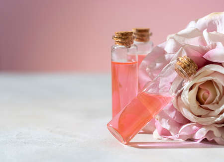 Perfumed Rose Water or essential oil in glass bottle and rose flower on a light background. Selective focus, copy spaceの写真素材
