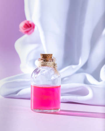 Bottle essential oil or rose water with draped white silk fabric. Spa and aromatherapy cosmetic concept. Copy spaceの写真素材