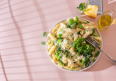 Fusilli with with broccoli, basil and parmesan cheese on beige background. Proper nutrition. Sports...