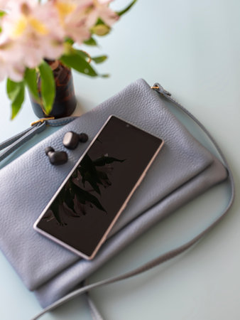 Women's blue bag made of genuine leather. Fashionable cross body lies on on blue background with...