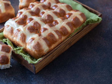 Homemade Hot Cross Buns on a wooden board on brown background. Traditional Easter food. Easter holiday concept. British foodの写真素材