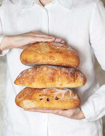 Female baker holds home made artisan organic bread fresh from the oven. Homemade sourdough bread. Homemade food. Food preparation.の写真素材