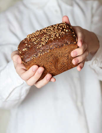 Traditional Russian rye Borodino bread. Female baker holds home made artisan organic bread fresh from. Homemade sourdough bread. Food preparation.の写真素材