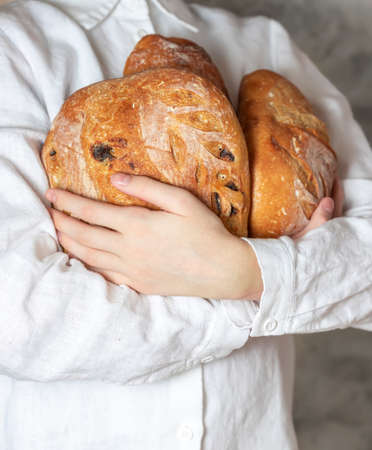 Female baker holds home made artisan organic bread fresh from the oven. Homemade sourdough bread. Homemade food. Food preparation.の写真素材