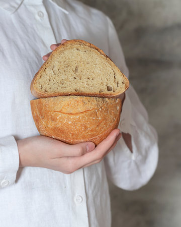 Female baker holds home made artisan organic bread fresh from the oven. Homemade sourdough bread. Homemade food. Food preparation.の写真素材