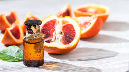 Bottle of essential oil and citrus fruits, sunlight and shadows. Citrus oil for skin care, spa, aromatherapy and natural medicine. Long harsh shadows.の写真素材