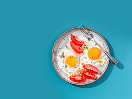 Two fried eggs with toast and vegetables on colorful background. Breakfast concept. Healthy vegetarian food. Close up, copy spaceの写真素材