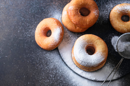 Sweet donuts with powder sugar on black background. Food concept. Copy space.