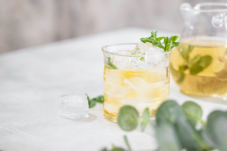 Summer iced green tea with fresh mint on light table. Food in motion concept. Summer cold drink cocktail. Copy spaceの写真素材
