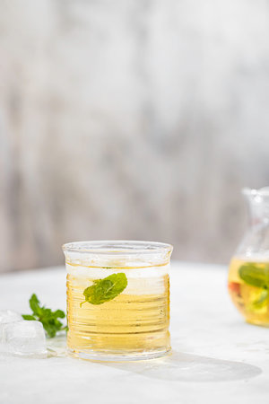Summer iced green tea with fresh mint on light table. Food in motion concept. Summer cold drink cocktail. Copy spaceの写真素材