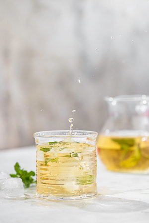 Summer iced green tea with fresh mint on light table. Food in motion concept. Summer cold drink cocktail. Copy spaceの写真素材