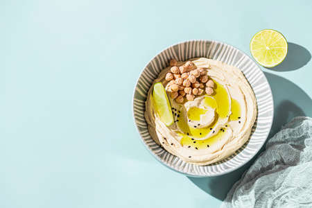 Chickpea hummus with olive oil and lime on a ceramic plate. Homemade classic hummus. Chickpea dishes, vegetarian dish. Selective focus, copy space.の写真素材