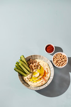 Chickpea hummus with olive oil and cucumbers on a ceramic plate. Homemade classic hummus. Chickpea dishes, vegetarian dish. Selective focus, copy space.の写真素材