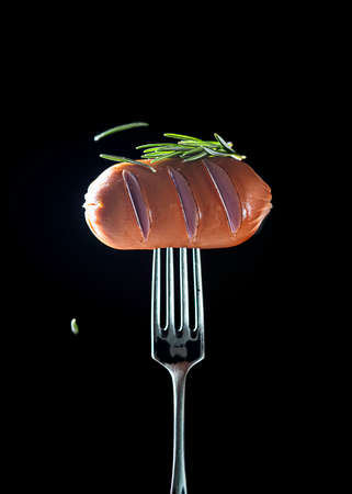Hot juicy meat sausages on a fork on a black background. Tasty food. Copy space.の写真素材