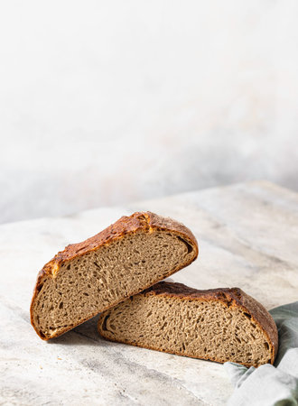 Freshly baked rye bread on a light concrete background, linen napkin. Place for your text. Freshly...