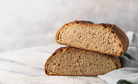 Freshly baked rye bread on a light concrete background, linen napkin. Place for your text. Freshly...