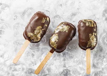 covered with chocolate, with a leaf of edible gold on top on an icy background with snow.  sweet...