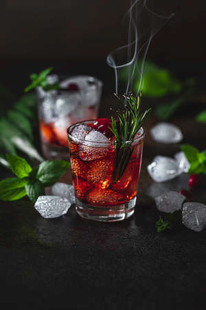 Berry alcoholic cocktail liqueur, vodka, ice and rosemary. Refreshing cool drink, berry liqueur or red alcoholic cocktail. Selective focusの写真素材