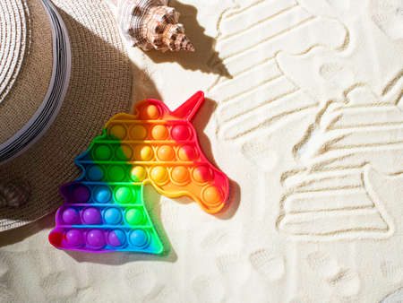 Pop up toy, rainbow colors, in the form of a unicorn. Multi-colored, sensory anti-stress toy fidget pop up on the beach. Selective focusの写真素材