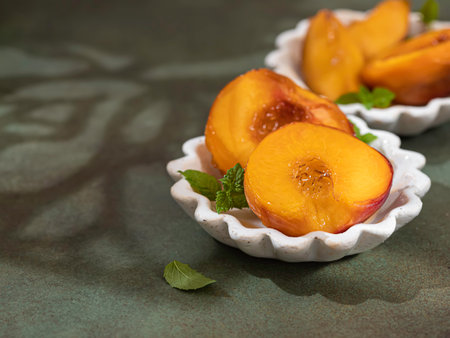 Caramelized peaches with honey, with mint leaves on a concrete background with shadows. Summer...