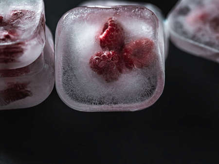 Raspberry frozen in the ice cube on black background. Fresh healthy summer eating.の写真素材