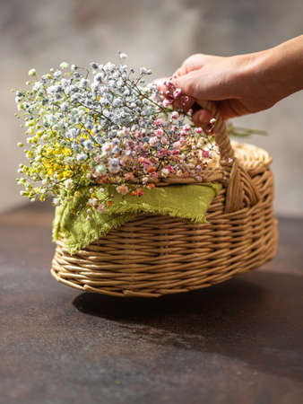 Wicker basket of straw with flowers and a woman's hand. Natural eco materials. Zero West. Place for textの写真素材