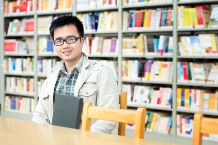 Handsome man sitting and reading in libraryの写真素材