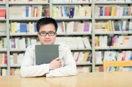 Handsome man sitting and reading in libraryの写真素材
