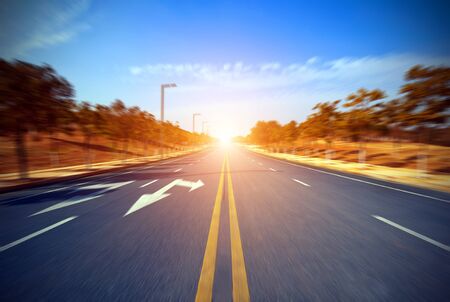 Asphalt blurry road and bright blue sky with cloudsの写真素材