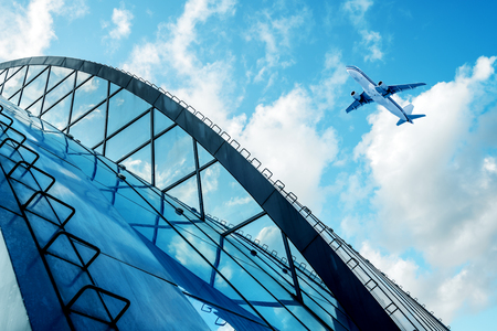 Shot of airplane flying above glass office buildings. Fisheye lens effect.の写真素材
