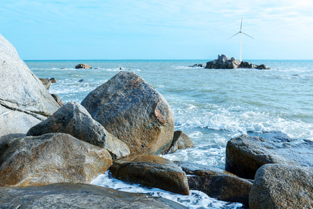 The vast expanse of the sea, and the distant reef above the wind turbine.の写真素材