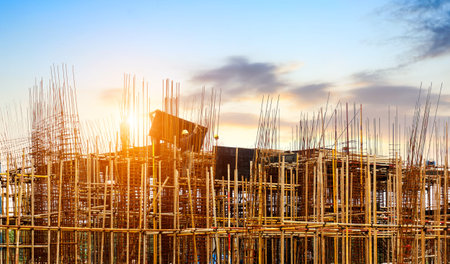 Construction site, silhouettes of construction industry workers on scaffolding against the sunset...