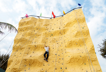 Asian young man practicing indoor rock climbingの写真素材
