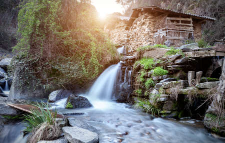 A water mill in a remote mountain area, a mechanical device that uses a waterfall as its power source.の写真素材